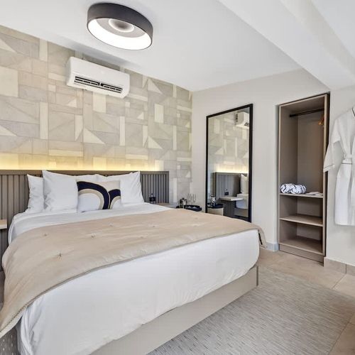 Modern and minimalist bedroom featuring a large, comfortable bed with crisp white linens and plush pillows, accented by a stylish beige headboard.