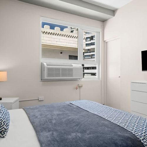 Cozy and contemporary. This inviting bedroom offers a comfortable bed with modern bedding, providing a bright and relaxing space perfect for your stay.