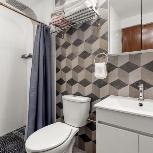 renovated bathroom with wall mirror, white cabinets, wc, rainshower
