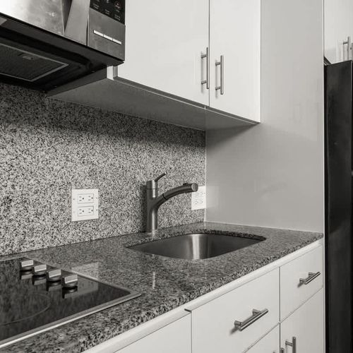 livingroom with kitchen , stainless steel fridge, air conditioner, sofabed, seats, ceiling fan, microwave,  reading lamps, cabinets