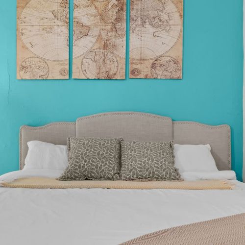 main bedroom with double bed, wall art, blue wall, large closet with mirror. bed side table with reading lamp and airconditioner