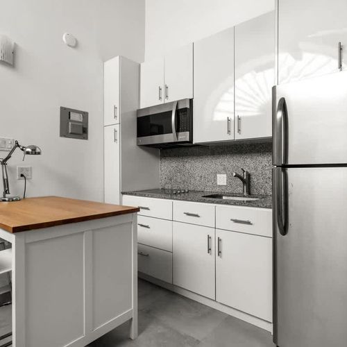 livingroom with kitchen , stainless steel fridge, air conditioner, sofabed, seats, ceiling fan, microwave,  reading lamps, cabinets