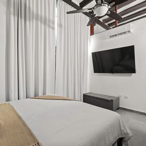 Enjoy the convenience of a flat-screen TV and efficient air conditioning, while the comfortable bed and sheer curtains create a tranquil retreat.