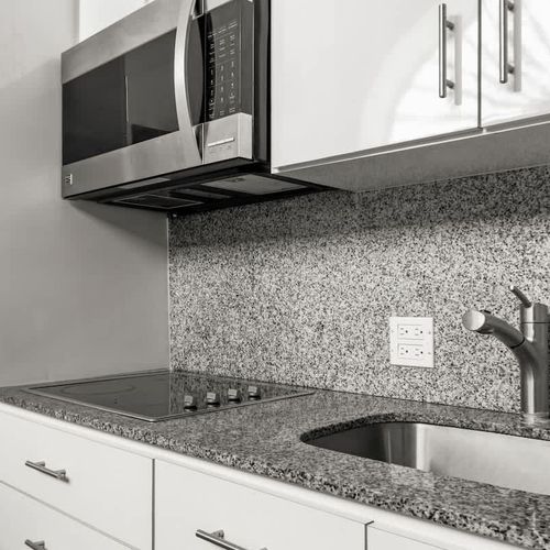 livingroom with kitchen , stainless steel fridge, air conditioner, sofabed, seats, ceiling fan, microwave,  reading lamps, cabinets