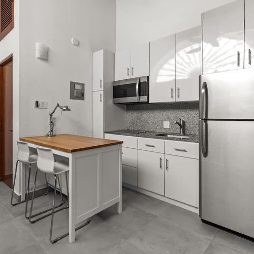 livingroom with kitchen , stainless steel fridge, air conditioner, sofabed, seats, ceiling fan, microwave,  reading lamps, cabinets