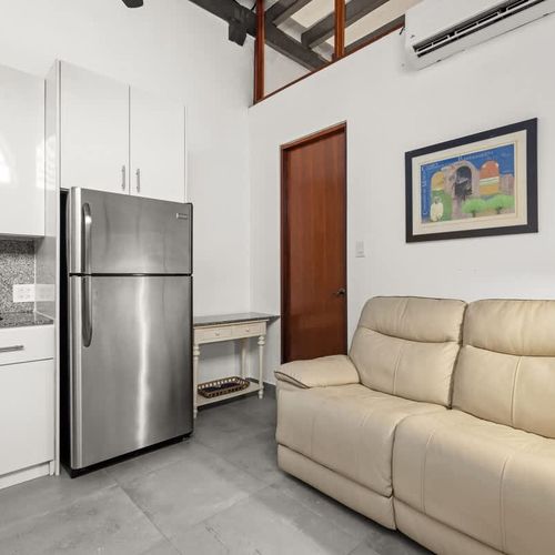livingroom with kitchen , stainless steel fridge, air conditioner, sofabed, seats, ceiling fan, microwave,  reading lamps, cabinets