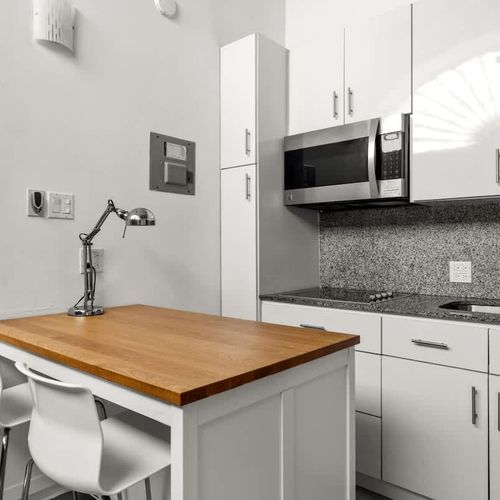 livingroom with kitchen , stainless steel fridge, air conditioner, sofabed, seats, ceiling fan, microwave,  reading lamps, cabinets