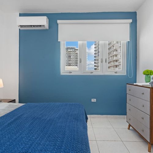 A spacious main bedroom with a comfortable bed and calming blue accent wall.