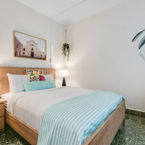 A comfortable sleeping space with tasteful art and a large reflection.