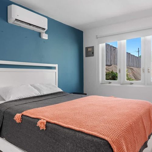 bright bedroom with queen sized bed, blue wall decor, air conditioner, window with pool views, nice comforter and soft bed linens, cabinets and hangers, long wall mirror