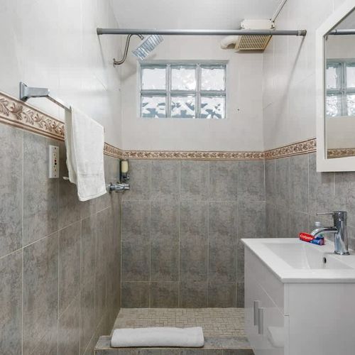 Experience the peaceful ambiance of this modern bathroom sanctuary, showcasing stylish grey tiled walls adorned with intricate patterns.