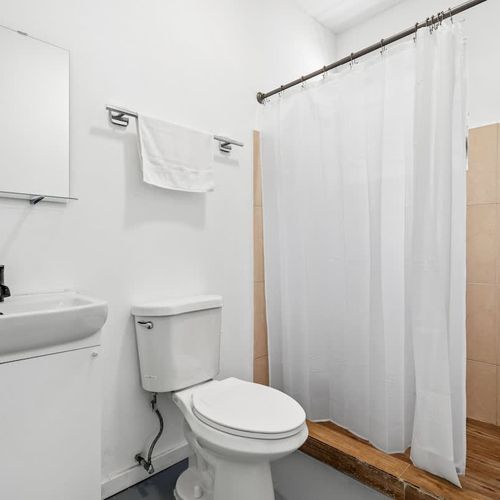 Step into a serene retreat with our well-lit bathroom, boasting a modern sink, full-sized mirror, and spacious shower.