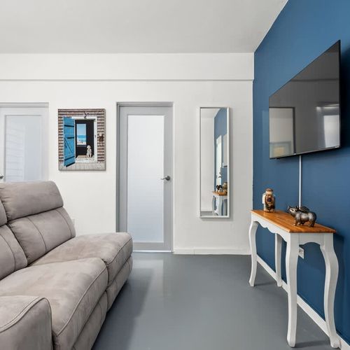 Step into a serene urban oasis with this modern living room, boasting a plush grey sofa, vibrant blue accent wall, and sleek decor.