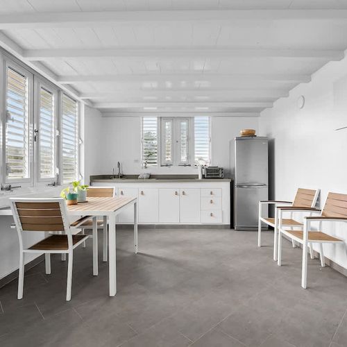 modern kitchen with stainless steel fridge and faucet, dining table and wall art