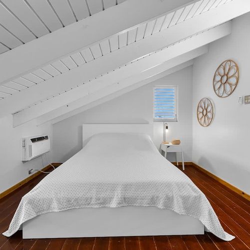 main bedroom with air conditioner, desk, wall art and windows