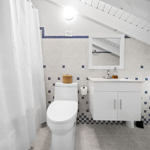 Clean, coastal, and charming. Bright bathroom with fun tile details and everything you need to refresh after a beach day.