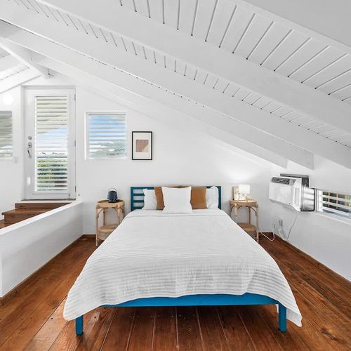 bedroom with bed and private balcony, air condiotioner, wall art and night table