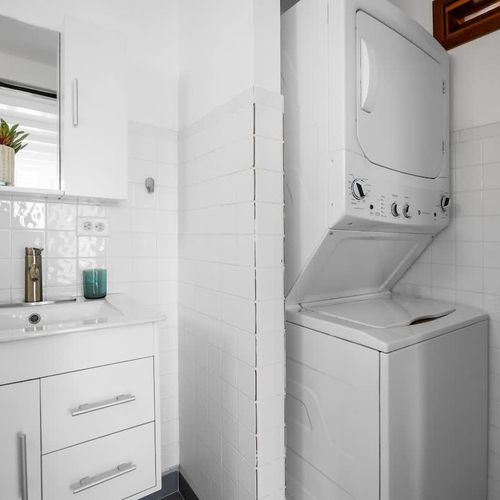 Refresh in the modern bathroom with a spacious shower, stylish vanity, and built-in laundry area – great for extended stays or packing light.