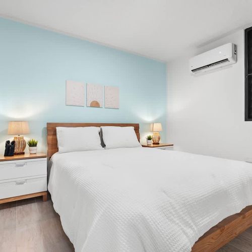bed with wall art, air conditioner, bedside tables, lamps