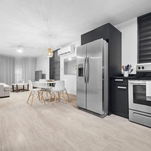 open kitchen area with double door stainless steel fridge, oven, air conditioner, balcony, sofa, dining table, utensils , ceiling lamp