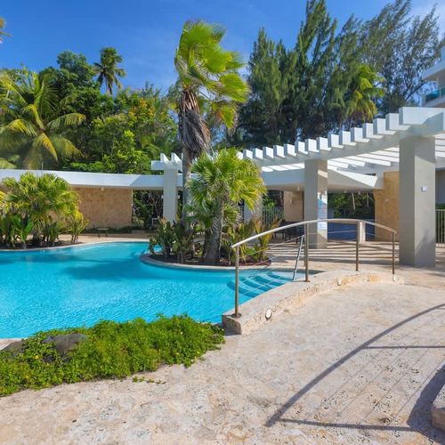 Dive into paradise! Our sparkling pool is surrounded by lush tropical landscaping, offering a refreshing escape and a perfect spot for sunbathing and relaxation.
