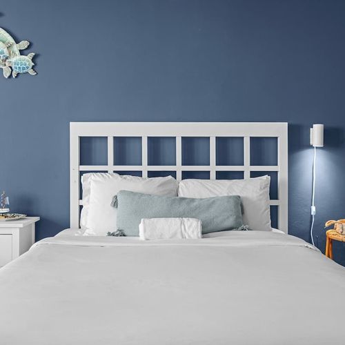 Experience ultimate comfort in this beautifully designed bedroom, featuring a striking accent wall and ample natural light pouring in from the large glass doors.