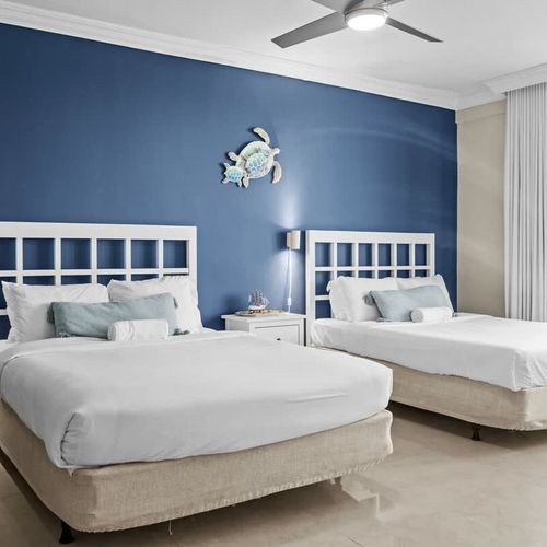 Sleep soundly in this tranquil bedroom featuring two comfortable beds and a ceiling fan for optimal comfort, all while enjoying panoramic water vistas.