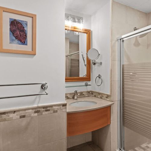 Your pristine bathroom offers a well-lit vanity and a sleek shower design for ultimate comfort.