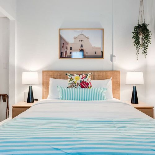 Cozy, modern bedroom, with wall painting and big mirror. Thoughtfully designed for ultimate comfort and relaxation.