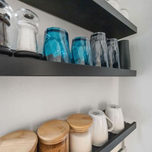 Imagine effortlessly organizing your essentials in this beautifully designed space.  Crisp white walls provide a fresh backdrop for your personal style, while the striking black shelving offers a contemporary touch and clever storage.