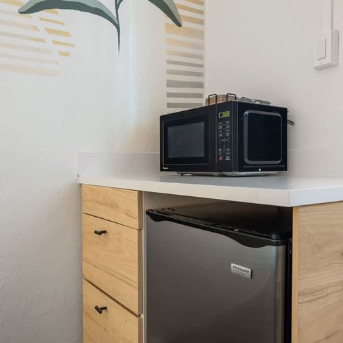 Whip up your favorite snacks and meals effortlessly in this sleek, minimalist kitchen, complete with a compact oven and handy mini fridge for all your essentials.
