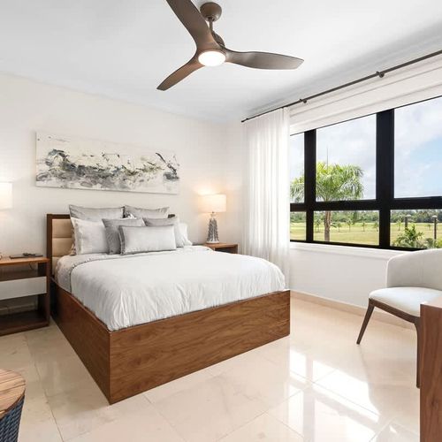 This tranquil bedroom is the perfect escape. The plush bed, wrapped in soft linens, and the neutral colors create a calming vibe. Large windows let in lots of natural light, offering beautiful views of the lush greenery and golf course. A cozy armcha
