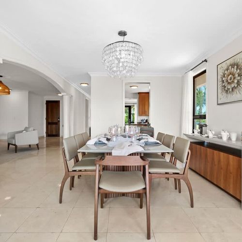 A luxurious and elegant dining room that exudes sophistication and style. The spacious room features a grand dining table, comfortably seating a large group of guests, and a stunning chandelier that adds a touch of opulence.  the large windows offer