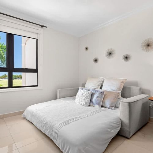 This bright and airy guest room features a comfortable sofa bed, perfect for accommodating extra guests. The neutral color palette creates a relaxing ambiance, while the large windows offer stunning views of the surrounding landscape.