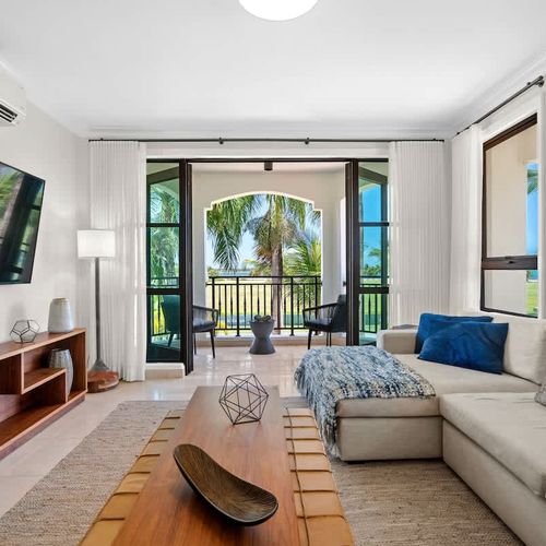 This living space is all about modern elegance and comfort. It features a plush sectional sofa, a sleek coffee table, and a big flat-screen TV, perfect for relaxing or entertaining. The standout feature is the amazing golf course view from the slidin
