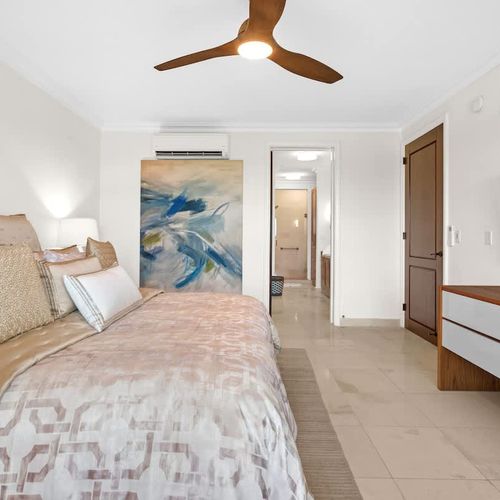 A  spacious bedroom is the perfect spot to relax. The king-sized bed, with its luxurious linens and neutral colors, creates a calm vibe. A modern ceiling fan and air conditioning keep you comfortable, and the large windows give you amazing views of t