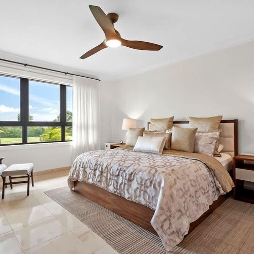 This cozy bedroom is all about relaxation and style. The king-sized bed with its soft linens and neutral headboard is super comfy. Big windows let in lots of natural light and offer great views of the golf course. A modern ceiling fan and air conditi