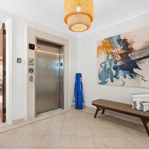 Sleek and modern elevator access. The foyer boasts contemporary design with a touch of coastal elegance, featuring a stylish bench and artwork.