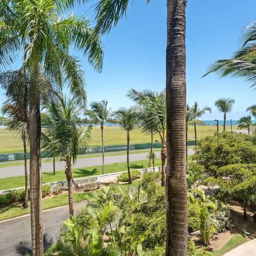 The vibrant blue sky and fluffy white clouds create a picturesque backdrop, inviting you to immerse yourself in the tranquility of this tropical paradise.