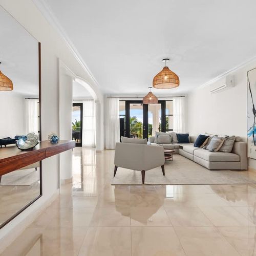 This chic living space is super inviting with its clean lines, neutral colors, and tons of natural light. The open layout makes the living and dining areas feel connected and roomy. A large abstract artwork adds a cool touch, and the comfy sofas and