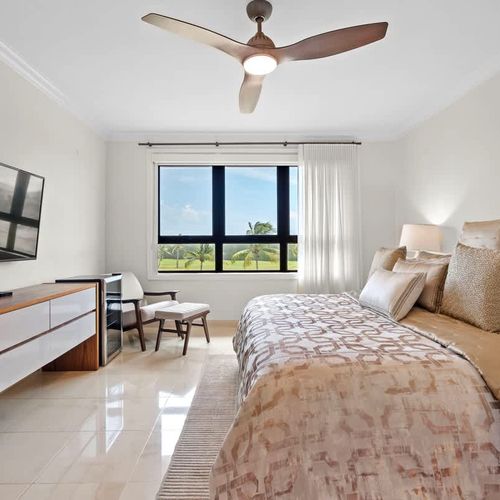 Large windows offer tranquil views while a ceiling fan ensures comfort.