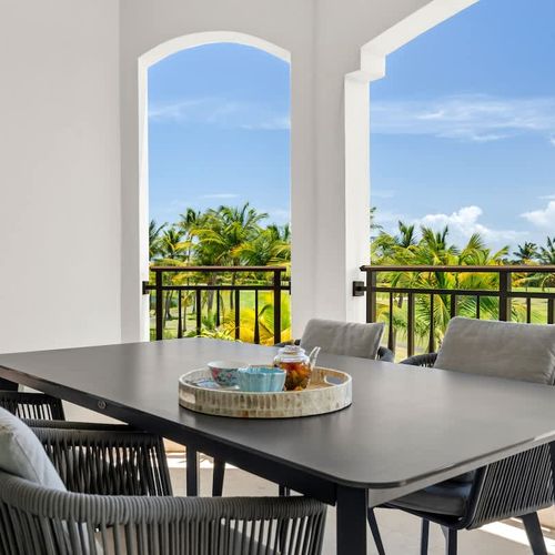 This spacious balcony is a great outdoor spot with a table for four, comfy chairs, and amazing views of the golf course and palm trees. The modern furniture and greenery make it perfect for meals or just soaking in the scenery.