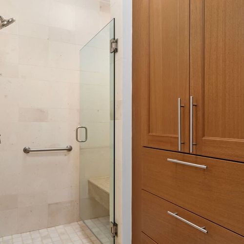 Spa-like shower with glass enclosure and built-in seating. Ample storage with additional cabinetry.