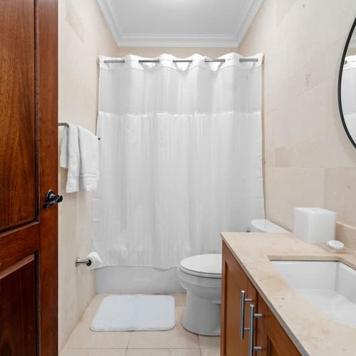 This inviting bathroom blends classic and modern design with a spacious tub, separate shower, and double vanity. Neutral colors and natural light create a serene atmosphere. Modern fixtures like a sleek mirror and brushed nickel showerhead, along wit