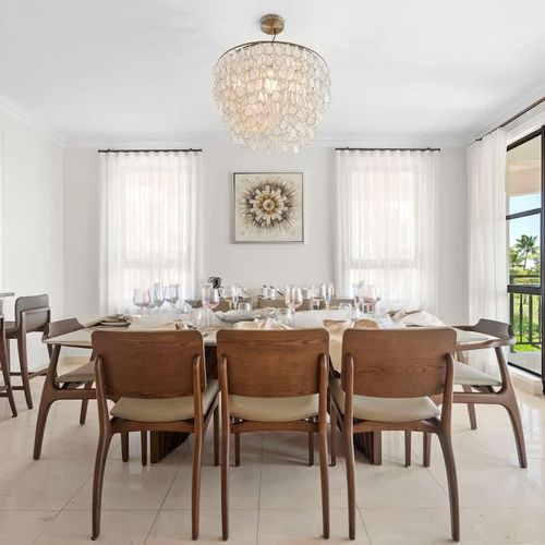 This stylish dining room is great for dinner parties or cozy meals. It has a big table that seats up to eight, and the modern chandelier gives it a chic touch. Large windows provide awesome views of the golf course, and the neutral colors keep things
