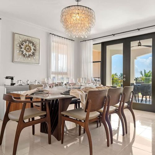 This elegant dining room boasts stunning outdoor views and a sophisticated ambiance. The modern dining table, paired with comfortable chairs and a dazzling chandelier, creates an inviting atmosphere for entertaining guests or enjoying intimate meals.