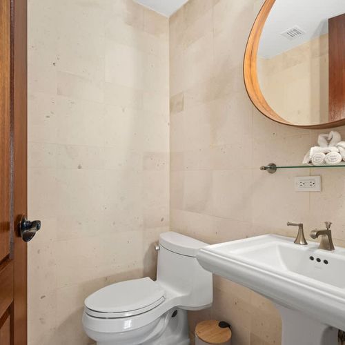 Sleek and modern powder room. Featuring a stylish pedestal sink, a contemporary mirror, and elegant fixtures, this compact space is perfect for guests.
