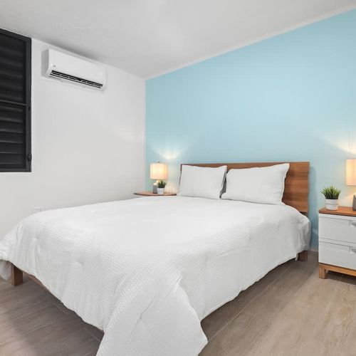 Peaceful bedroom with modern decor and cooling A/C.