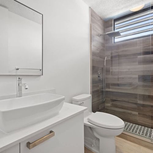 Sleek bathroom featuring a stylish vessel sink & spacious shower.