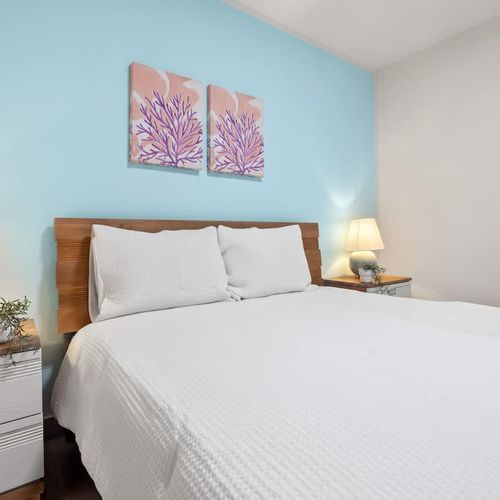 Inviting, pristine queen bed with charming coastal decor for restful nights.